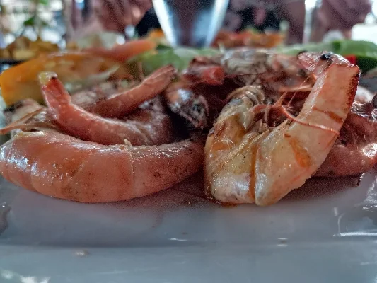 Bord met vers bereide garnalen, vergezeld van groenten en kruiden, geserveerd in een restaurant